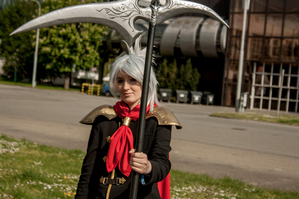 akela dressed as sice from final fantasy type-0 with tall black handled scythe. black suit red ascot gold shoulder pads off silver wig.