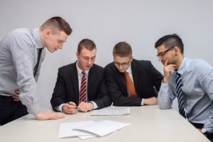 four men looking to the paper