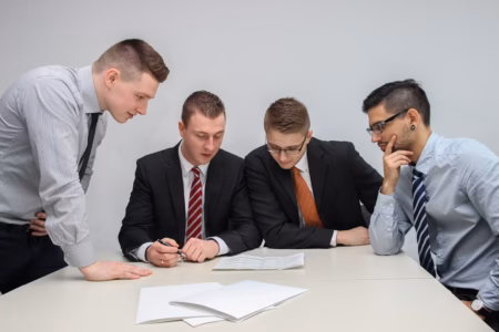 four men looking to the paper
